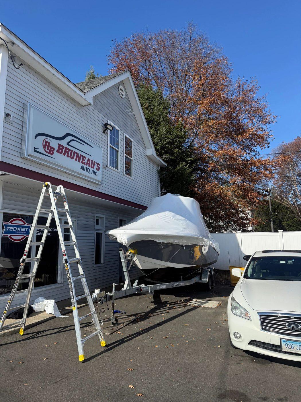 Shrink wrapped boat and a car outside Bruneau's Auto