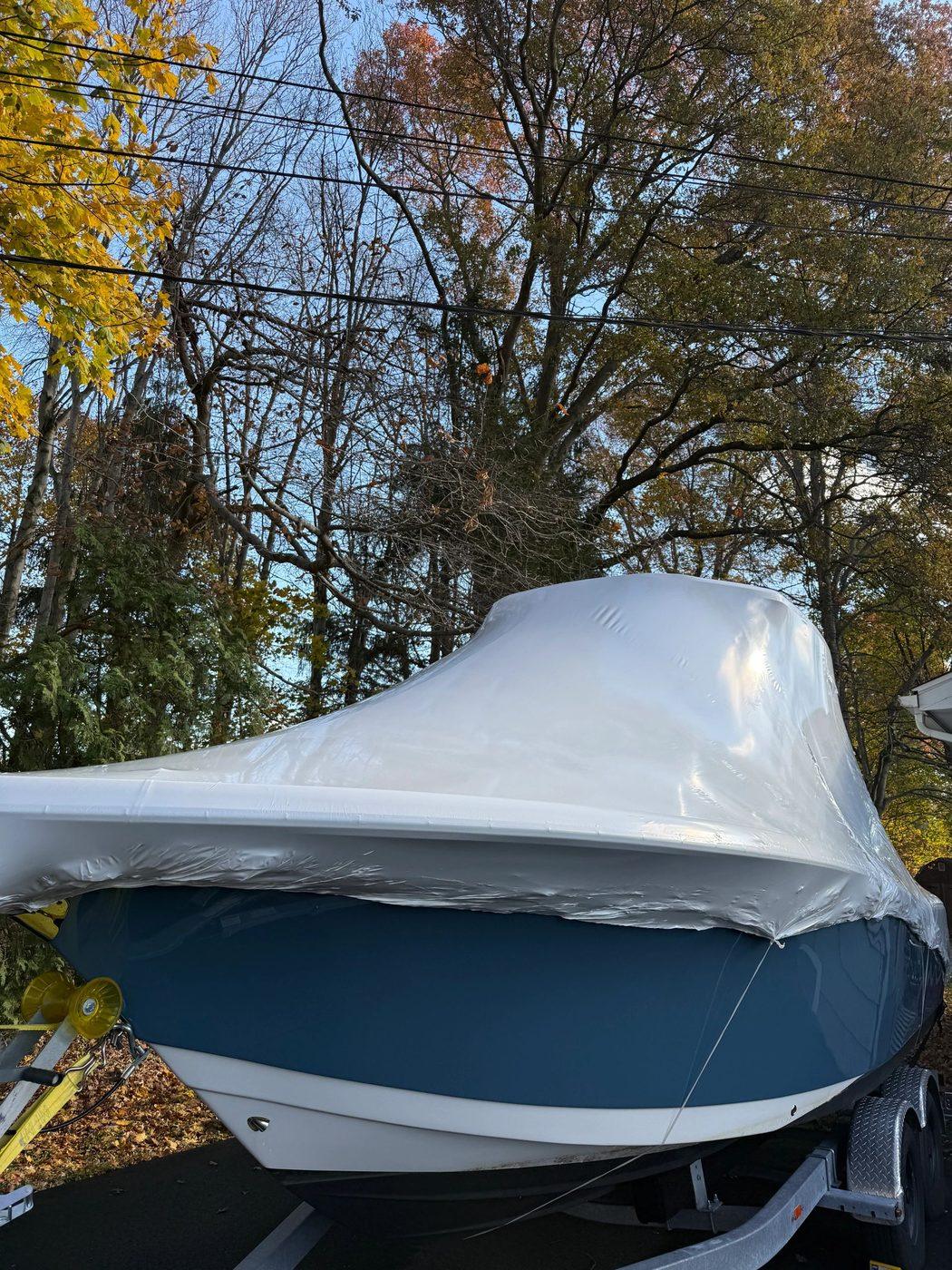 Boat covered in white shrink wrap on a trailer