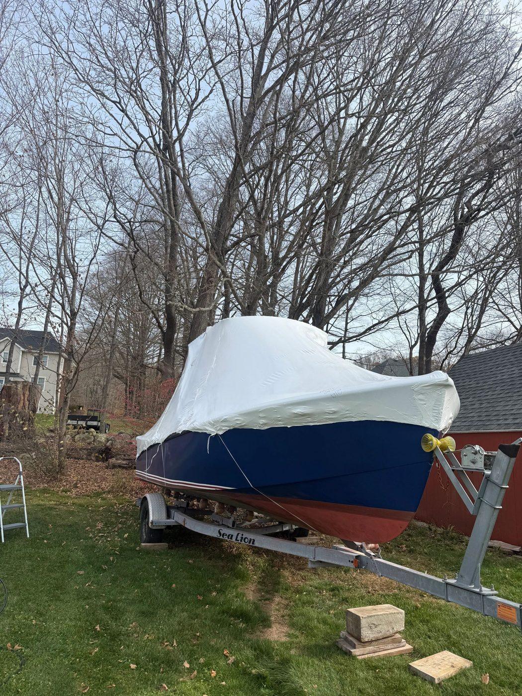 Boat covered with white shrink wrap on a trailer